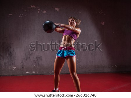 Attractive female athlete performing a kettle-bell swing.