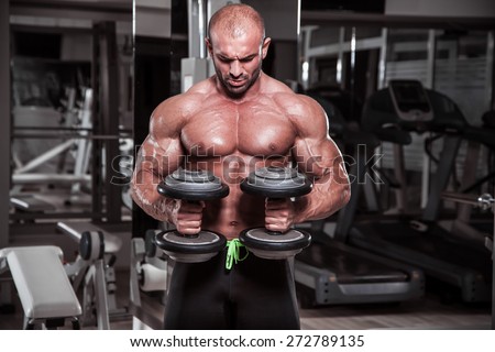 Body Builder performing exercise for biceps with weights in both hands.