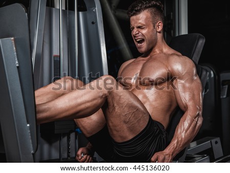 Handsome strong man performed leg press in the gym.