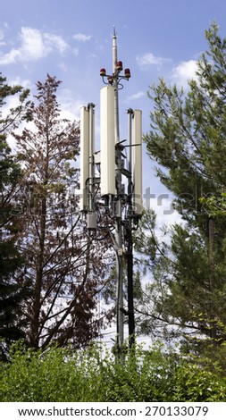 A telecommunications wireless cell phone antennas tower and trees.