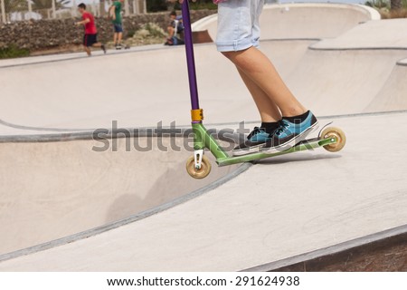 Boy in a skate park with a push scooter.