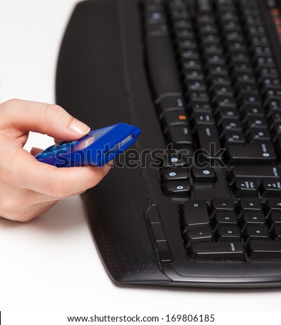Woman hands holding blue bank security token in front of black keyboard.