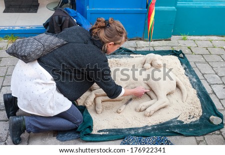 GALWAY, IRELAND - JULY 29, 2009: Street artist working on a sand sculpture of dogs. The Galway Arts Festival takes place in July and is one of the biggest arts festivals in Ireland.