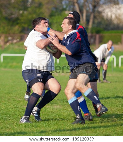 ZAGREB, CROATIA - MARCH 29, 2014: Friendly rugby match RC Zagreb Old Lions in white jersey (CRO) and Reigate RFC in blue jersey (UK). Unidentified players run for ball.