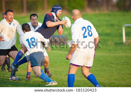ZAGREB, CROATIA - MARCH 29, 2014: Friendly rugby match RC Zagreb Old Lions in white jersey (CRO) and Reigate RFC in blue jersey (UK). Unidentified players run for ball.