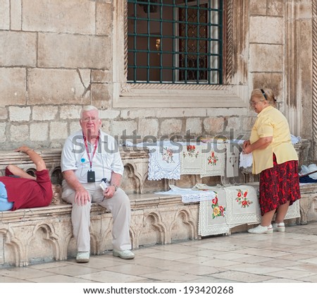 DUBROVNIK, CROATIA - OCTOBER 10, 2009: Old woman selling hand made decorative clothes on Stradun,  main street in Dubrovnik\'s Old Town.