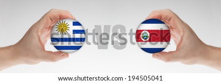Man's hands holding styrofoam balls with Uruguay and Costa Rica flag against the white background.
