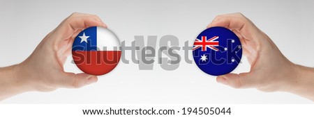 Man\'s hands holding styrofoam balls with Chilean and Australian flag against the white background.