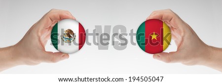 Man\'s hands holding styrofoam balls with Mexican and Cameroon flag against the white background.