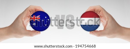Man\'s hands holding styrofoam balls with Australian and Dutch flag against the white background.