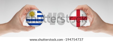 Man\'s hands holding styrofoam balls with Uruguay and English flag against the white background.