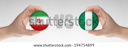 Man\'s hands holding styrofoam balls with Iranian and Nigerian flag against the white background.