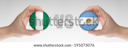 Man\'s hands holding styrofoam balls with Nigerian and Argentinian flag against the white background.