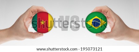 Man\'s hands holding styrofoam balls with Cameroon and Brazilian flag against the white background.