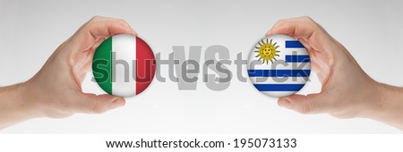Man\'s hands holding styrofoam balls with Italian and Uruguay flag against the white background.