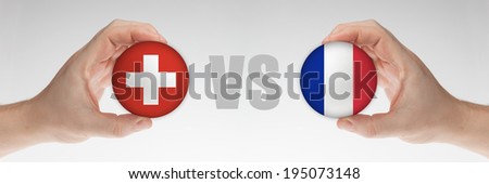 Man's hands holding styrofoam balls with Swiss and French flag against the white background.