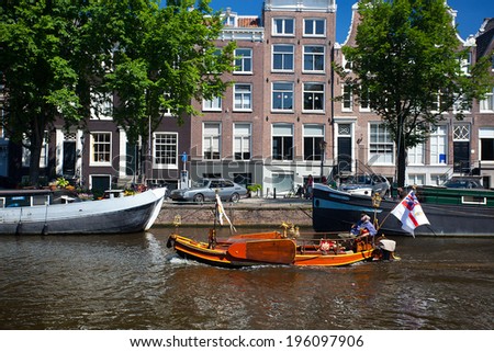 AMSTERDAM, NETHERLANDS - AUGUST 8, 2012: Elderly man enjoying a boat ride boat in a canal.