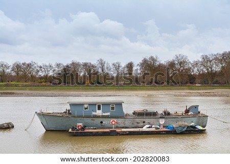LONDON, UNITED KINGDOM - DECEMBER 28, 2011: Boat on river Thames during the low tide near Albert Bridge.  It is the longest river in England and the second longest in the United Kingdom.