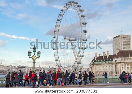 LONDON, ENGLAND - DECEMBER 28, 2011: Group of tourists on the bridge with London eye in background. London eye is the highest Ferris wheel in Europe (135m)