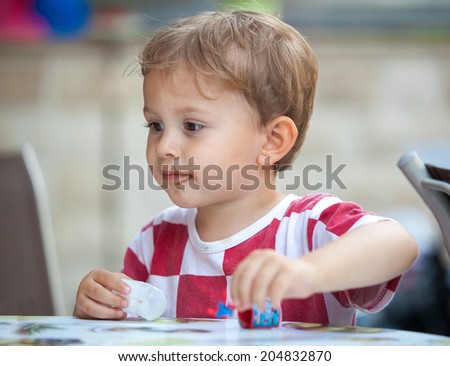 Cute little boy with chocolate smudges on face wearing Croatian jersey shirt and playing with toys.