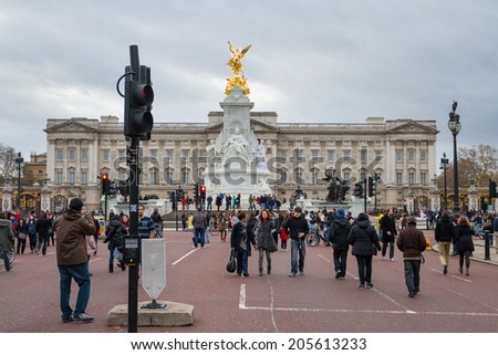 LONDON, ENGLAND - DECEMBER 25, 2011: Tourists in front of Buckingham palace. Palace has served as official London residence of Britain\'s sovereigns since 1837 and today is administrative headquarters