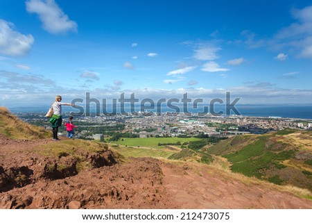 EDINBURGH, SCOTLAND: AUGUST 4, 2014: Tourist pointing finger in distance on Arthur\'s seat in Holyrood Park. Arthur\'s seat is popular destination for hiking and enjoying nature.