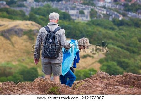 EDINBURGH, SCOTLAND: AUGUST 4, 2014: Elderly couple climbing down the hill in Holyrood Park. Arthur\'s seat is popular destination for hiking and enjoying nature.