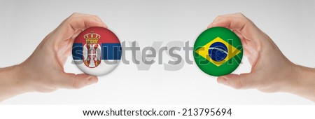 Man\'s hands holding styrofoam balls with Serbia and Brazil flag against the white background.