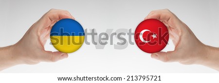 Man\'s hands holding styrofoam balls with Ukraine and Turkey flag against the white background.