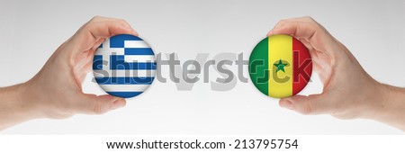 Man\'s hands holding styrofoam balls with Greece and Senegal flag against the white background.