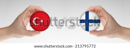 Man\'s hands holding styrofoam balls with Turkey and Finland flag against the white background.