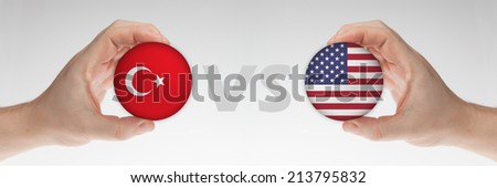 Man\'s hands holding styrofoam balls with Turkey and USA flag against the white background.
