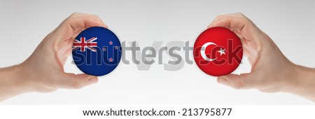 Man\'s hands holding styrofoam balls with New Zealand and Turkey flag against the white background.