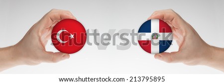 Man\'s hands holding styrofoam balls with Turkey and Dominican Republic flag against the white background.