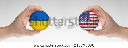 Man\'s hands holding styrofoam balls with Ukraine and USA flag against the white background.