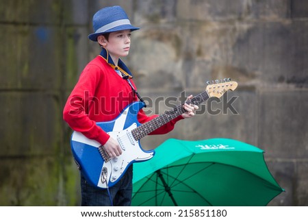 EDINBURGH, SCOTLAND: AUGUST 6, 2014: Little boy playing electric guitar painted as Scottish flag on Fringe festival. Fringe is the very popular and largest arts festival in the world.