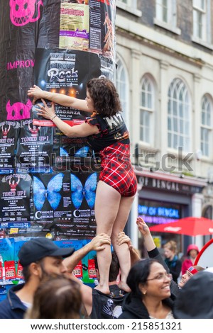 EDINBURGH, SCOTLAND: AUGUST 6, 2014: Girl in Kiss costume placing posters on post during Fringe festival. Fringe is the very popular and largest arts festival in the world.
