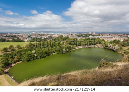 Panoramic view on St. Margaret\'s lake and city from hills in Holyrood Park. Park\'s highest point Arthur\'s seat is popular destination for hiking and enjoying nature.