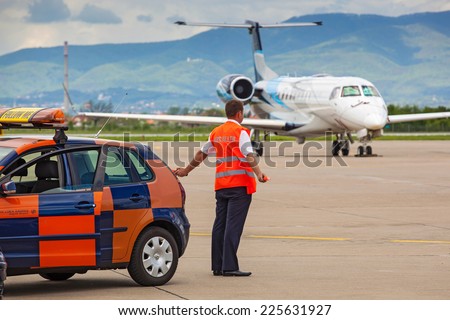 ZAGREB, CROATIA - APRIL 28, 2013: Aircraft marshaller standing by the Follow Me car at Pleso Airport.