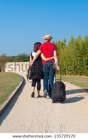 Young couple walking down the gravel road on a sunny day.