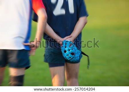 Rugby player holding Scrum cap. Post processed with radial blur zoom effect.