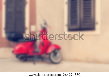 Red scooter parked by the wall in the empty street. Post processed with blur and vintage filter.