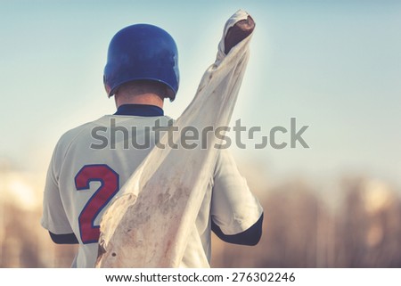 Baseball player holding bat with white rag on it. Post processed with vintage filter.