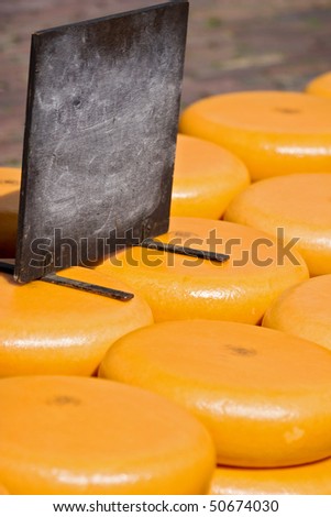 Blank black board on bunch of cheese wheels