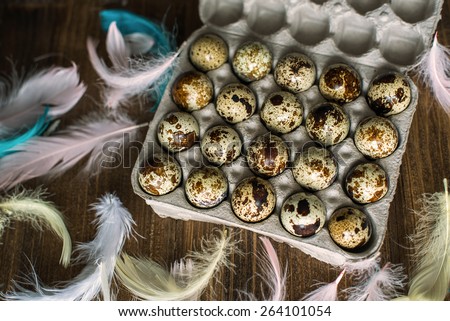 Packing quail eggs and colored feathers on a wooden table