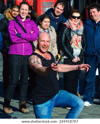 EDINBURGH, SCOTLAND -  11 APRIL, 2015: Street Artist performs with a lighted torch on the Royal Mile, Edinburgh