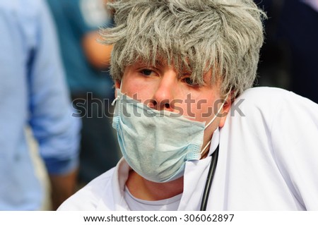 EDINBURGH, SCOTLAND - AUGUST 8, 2015: Man wearing face mask and hospital scrubs on the Royal Mile during the Edinburgh International  Festival