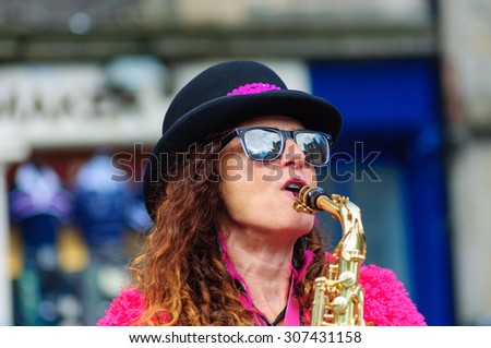 EDINBURGH, SCOTLAND - AUGUST 15, 2015: Female musician from The Ambling Band playing the saxophone at the Grassmarket during the Edinburgh International Fringe Festival