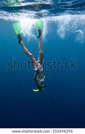 Young woman diving on a breath hold and fining in blue transparent sea