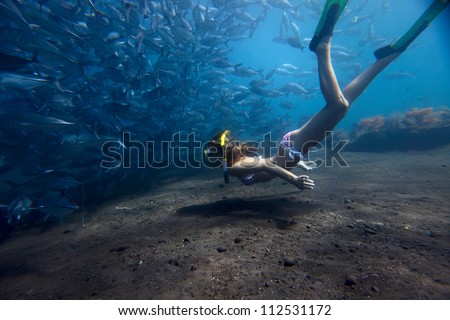 Young woman fining over bottom by school of a Jack Fish on a breath hold